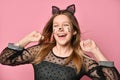 Adolescent in black dress, headband like cat ears, face painting. She posing on pink background. Close up Royalty Free Stock Photo