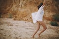 Joyful boho girl in white summer dress walking on beach. Carefree young woman relaxing on seashore. Summer vacation. Mindfulness