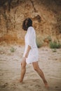 Joyful boho girl in white summer dress walking on beach. Carefree young woman relaxing on seashore. Summer vacation. Mindfulness