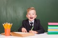 Joyful boy in class near empty green chalkboard Royalty Free Stock Photo