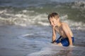 Joyful boy near the sea plays with the waves.