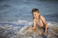 Joyful boy near the sea plays with the waves.