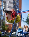 Joyful boy swinging on swing with parents behind. Royalty Free Stock Photo