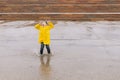 A joyful boy in a yellow cloak jumps with great pleasure in a po