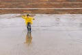 A joyful boy in a yellow cloak jumps with great pleasure in a po