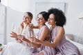 joyful bride and bridesmaids sitting in