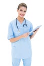 Joyful brown haired nurse in blue scrubs using a tablet pc Royalty Free Stock Photo