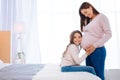 Joyful brunette girl listening her pregnant moms tummy Royalty Free Stock Photo