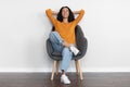 Joyful brunette woman resting in arm chair with closed eyes