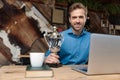 Joyful businessman holding his trophy and working on his laptop Royalty Free Stock Photo