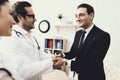 Joyful businessman shaking hands with doctor who cured ailment. Acknowledgments.