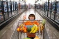 Joyful child boy in supermarket buys vegetables. Healthy food for children. Funny shopping. Cute kid with smile. A boy