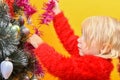 A joyful child decorates the Christmas tree with New Year`s toys