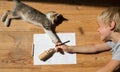 joyful child draws with pencils lying on the floor in a room on a bright sunny day in the company of a beloved kitten