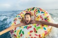 Child on inflatable ring ride on breaking wave. Travel lifestyle, swimming activities. Selective focus