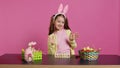 Joyful child putting bunny ears on her head and waving at camera Royalty Free Stock Photo