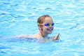 Joyful child in swimming glasses in the pool.