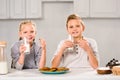 joyful children eating cookies and drinking milk at table Royalty Free Stock Photo