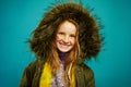 Joyful children girl in demi season winter jacket isolated on blue background. Smiling teenage child expresses sincere