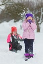 Joyful children playing in snow. Two happy girls having fun outside winter day Royalty Free Stock Photo