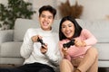 Joyful Chinese Couple Playing Video Game Sitting On Sofa Indoors Royalty Free Stock Photo