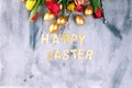 Joyful colorful spring background for a Happy easter with seasonal greeting text with rustic letter with flowers and tulips