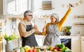 Joyful elderly couple have fun dancing and singing while cooking together in kitchen Royalty Free Stock Photo