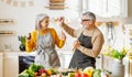 Joyful elderly couple have fun dancing and singing while cooking together in kitchen