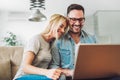 Joyful couple relax and work on laptop computer at modern living room