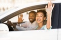 Joyful Couple Waving Hands Sitting In Car Having Road Trip