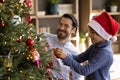 Joyful cute small kid boy decorating Christmas tree with father. Royalty Free Stock Photo