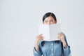 Joyful dark-haired girl covers her face with her white notebook