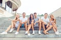 Joyful diverse best friends embracing and sitting on stairs while having fun on vacation