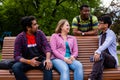 Joyful diverse company of college friends on wooden bench