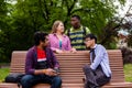 Joyful diverse company of college friends on wooden bench