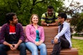 Joyful diverse company of college friends on wooden bench