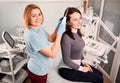 Cheerful hair specialist brushing woman hair with laser device. Royalty Free Stock Photo