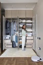 Joyful female putting box on shelf in cupboard enjoying housework at wardrobe organizing storage