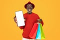 Joyful elderly black man in a red sweater and hat, showing a blank screen smartphone Royalty Free Stock Photo