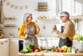 Joyful elderly couple have fun dancing and singing while cooking together in kitchen Royalty Free Stock Photo