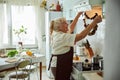 Cheerful old woman checking dried mushrooms in kitchen Royalty Free Stock Photo
