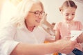 Joyful elderly lady embroidering with granddaughter