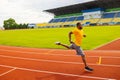 Joyful energetic African American sportsman athlete in yellow sportswear running at the stadium, preparing for