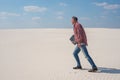 Joyful energetic man is walking through the desert with a laptop