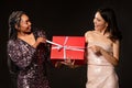 Joyful excited diverse ladies in nice outfits opening Christmas present Royalty Free Stock Photo