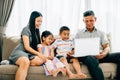 A cheerful family seated on a cozy sofa sharing a laptop parents and kids