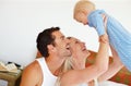 Joyful family moments. Two parents playing lovingly with their young son on their bed. Royalty Free Stock Photo