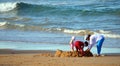 Joyful family, mother with two daughters building sandcastle on the beach Royalty Free Stock Photo