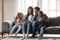 Joyful family sitting on couch, watching funny video on phone. Royalty Free Stock Photo