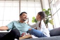 Joyful father playing with his little adorable daughter together, girl doing makeup to her dad by cosmetic, sitting on sofa in Royalty Free Stock Photo